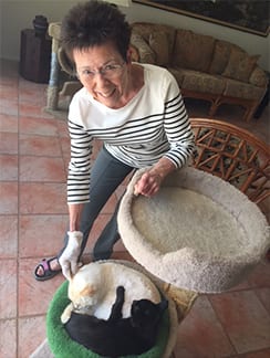 Camille stands over her two snuggling cats