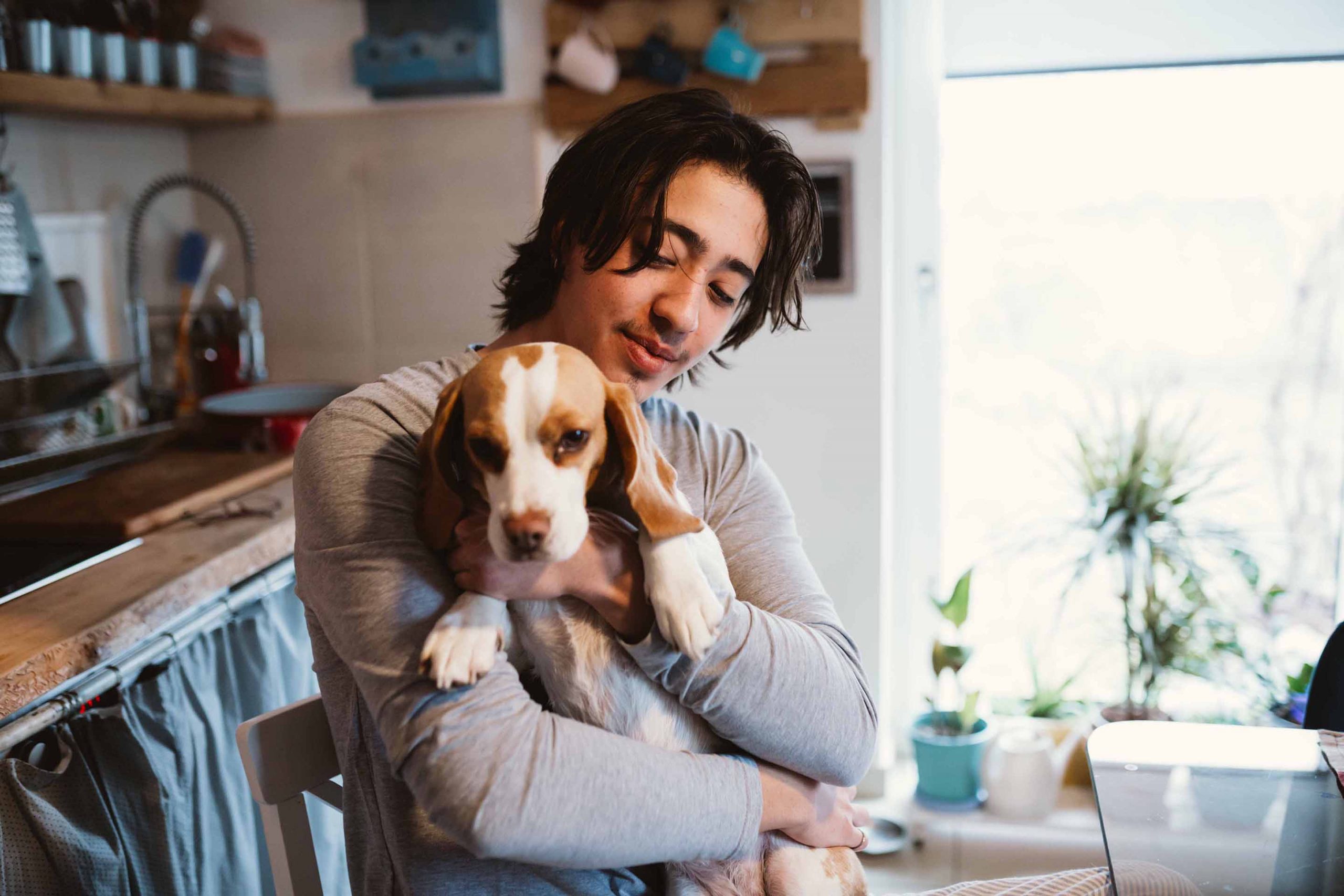 long man holding a small dog at breakfast